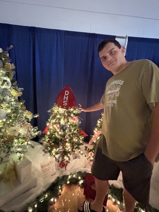 A person standing next to a christmas treeDescription automatically generated